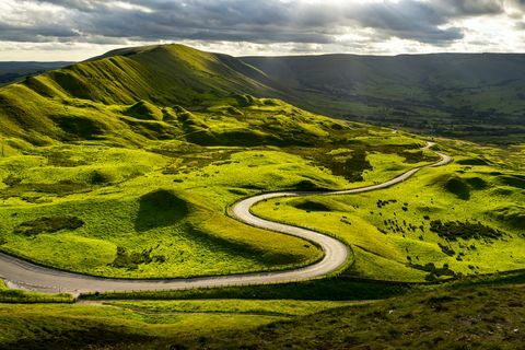 Besuchen Sie die Peak District Road, die sich durch grüne Hügel schlängelt