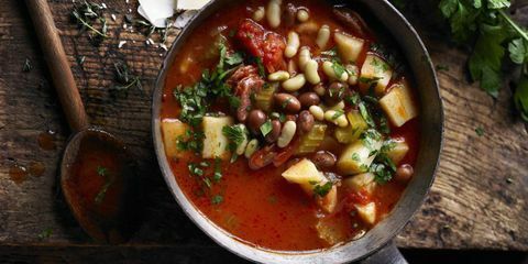 Pastinakensuppe mit italienischer Wurst und Tomate in der Wanne mit hölzernem Löffel dazu