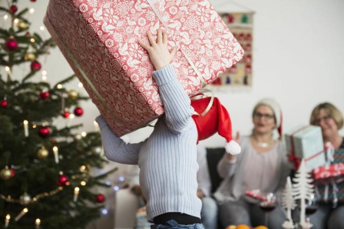 Kleiner Junge trägt zu Weihnachten einen großen Karton