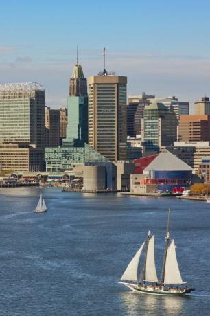 baltimore skyline und inner hafen mit drei segelbooten auf dem wasser im vordergrund und zwei segelbooten im hintergrund