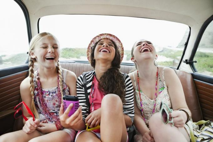 Drei Mädchen lachen auf dem Rücksitz eines Fahrzeugs