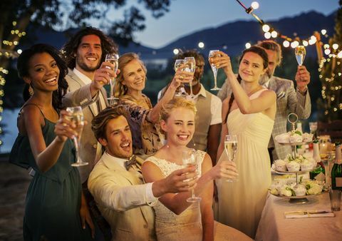 Hochzeitsgäste, die mit Champagner während des Hochzeitsempfangs im Garten rösten