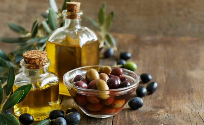 Olivenöl und Oliven auf Holzhintergrund