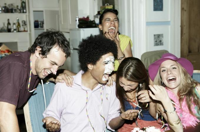 Mann mit Zuckerguss im Gesicht lacht mit Freunden