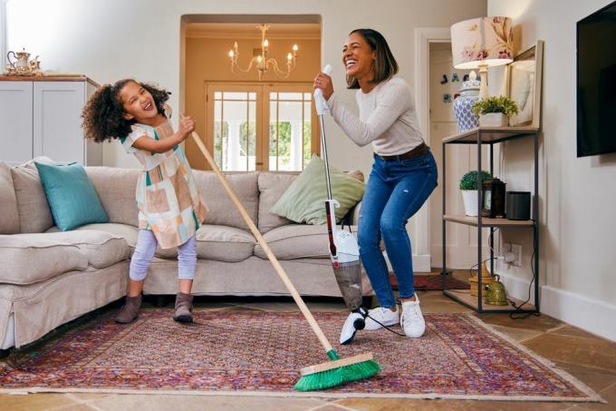 Aufnahme einer Mutter und Tochter, die sich beim Putzen des Wohnzimmers vergnügen