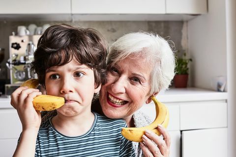 Großmutter und Enkel albern herum, benutzen Bananen als Telefone, lachen