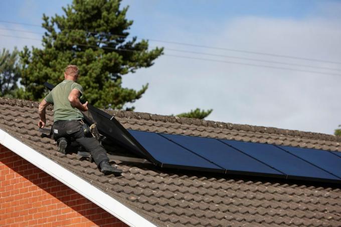 h0chn1 Mann installiert Solarpanel-Array auf dem Dach einer privaten Solarpanel-Anlage im Vereinigten Königreich