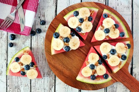 geschnittene, saftige wassermelonenpizza mit bananen, blaubeeren, nüssen und joghurt, oben ansicht auf holzservierbrett