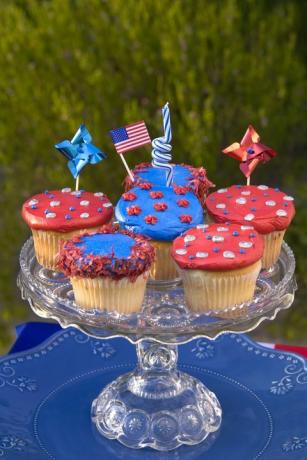 Sechs rot oder blau dekorierte Cupcakes auf einem Tortenständer aus geschnittenem Glas