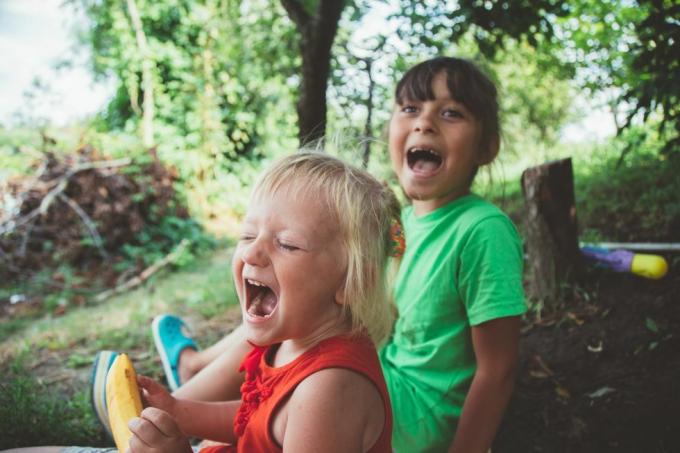 blonde glücklich lächelnde kleine Mädchen aufgeregt Lachen Hände in den Mund