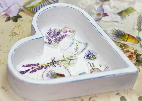 weiße hölzerne herzförmige Schachtel mit Decoupage-Bildern von Lavendel auf der Unterseite und ausgeschnittenem Papier