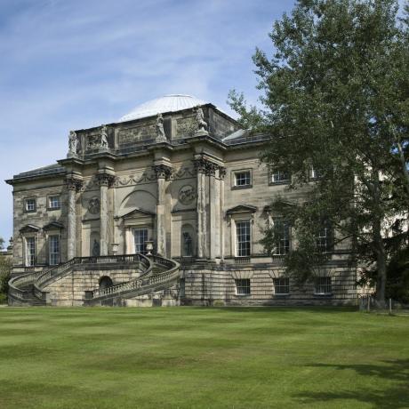 Die Südfassade von Kedleston Hall, Derbyshire, mit der Allerheiligenkirche auf der linken Seite. Der Bau des Hauses wurde 1759 von Paine und Brettingham begonnen, der Entwurf wurde jedoch von Robert Adam übernommen 1760 hat die Südfassade ein zentrales Element, das auf dem Konstantinsbogen basiert, kombiniert mit der niedrigen Kuppel des Pantheons. Die Allerheiligenkirche steht unter der Obhut des Kirchendenkmals Vertrauen