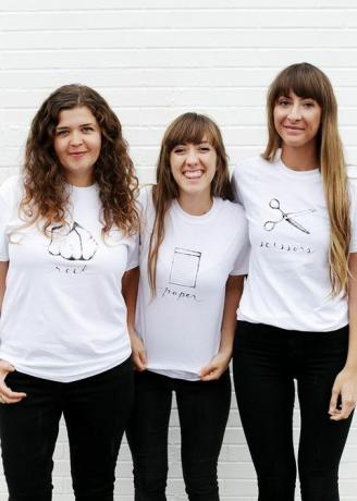 drei Frauen in weißen T-Shirts, mit Steinen, Papier oder Scheren geschrieben und abgebildet