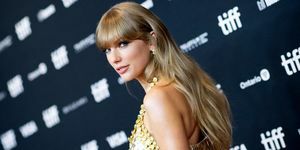 Taylor Swift blickt in goldenem Kleid auf dem roten Teppich über die Schulter