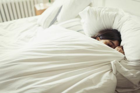 Müde junge Frau, die im Bett schläft