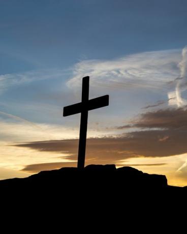 Holzkreuz auf einem Hügel bei Sonnenuntergang