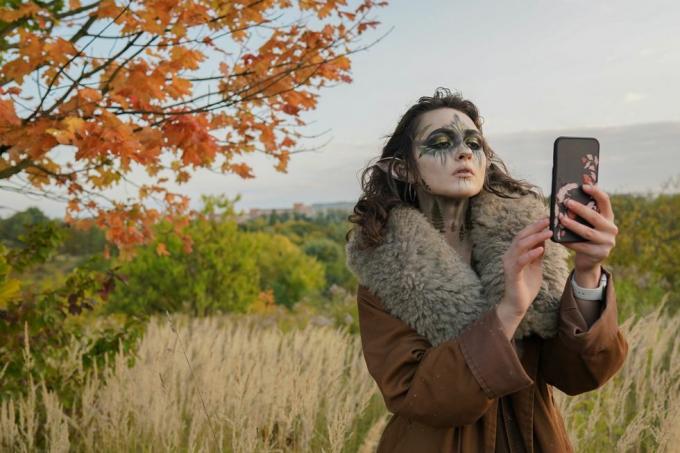 Frau im Halloween-Elfenkostüm macht ein Selfie im Wald