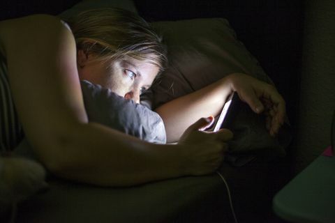 Frau, die intelligentes Telefon im Bett betrachtet