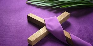 ein religiöses Kreuz und Palmblätter auf violettem Hintergrund