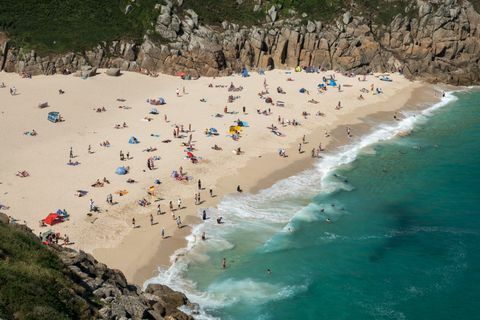 Die Menschen genießen das gute Wetter am Strand von Porthcurno in der Nähe von Penzance 