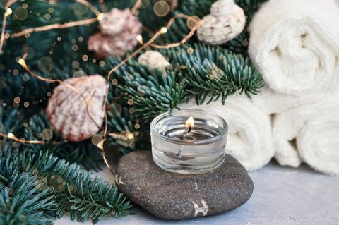 Weihnachts- und Neujahrskarte mit Tannenzweigen verziert mit Kugeln, Lichtern, Muscheln und Steinen für Spa-Behandlungen auf einem grauen Hintergrundschönheitskonzept