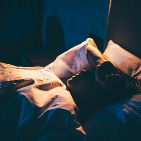 Frau mit Schlaflosigkeit junge Frau liegt auf dem Bett mit der Hand auf der Stirn