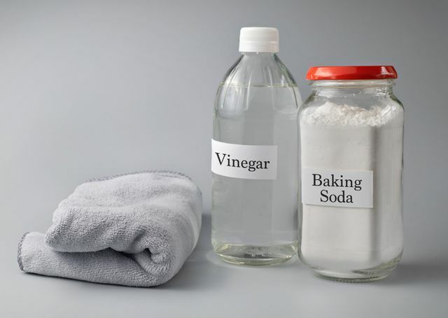 Nahaufnahme von Essig- und Backpulvertext auf einer Glasflasche vor grauem Hintergrund