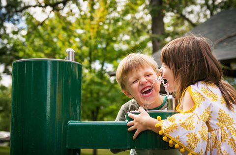 Zwei Kinder, die von einem Wasserbrunnenfoto trinken