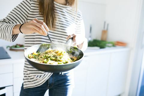 Junge Frau, die Wanne mit Teigwarenteller des strengen Vegetariers hält