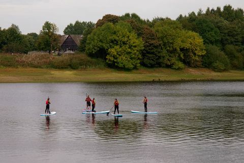 Besuchen Sie Peak District People, die lernen, auf dem Tittesworth Water Reservoir, Großbritannien, auf dem Paddelbrett zu stehen