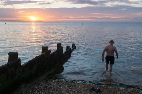 als die sonne über dem verblassenden tageslicht und den ruhigen wassern der themsemündung untergeht, betritt ein wilder meeresschwimmer für ihn das wasser regelmäßiger Abenddip am 18. Juli 2020 in Whitstable, Kent, England, Foto von Richard Baker in Bildern über Getty Images