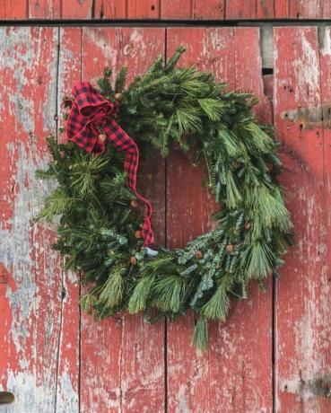 Nahaufnahme der Weihnachtsdekoration, die gegen rote Tür hängt