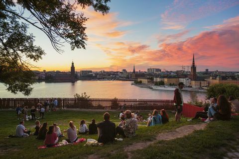 Leute, die Picknick in einem Park mit Panorama von Stockholm während des Sonnenuntergangs, Schweden haben