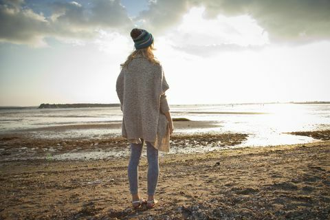 Junge Frau, die auf Bournemouth Strand, Dorset, Großbritannien anstarrt