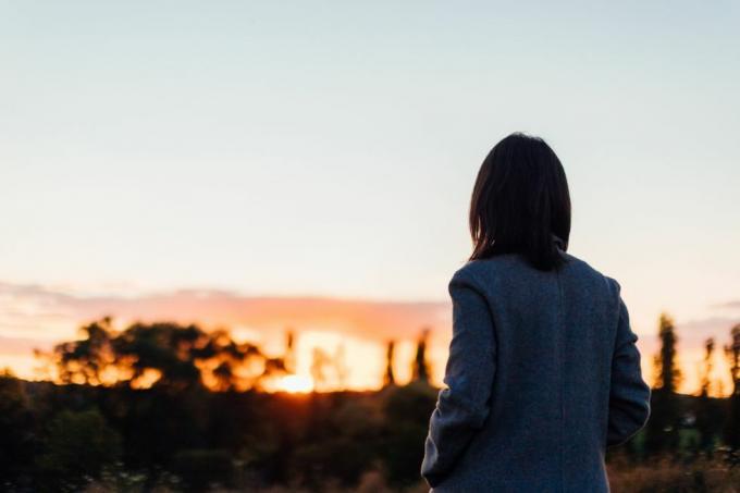 Rückansicht einer deprimierenden jungen Frau, die den Sonnenuntergang im Park beobachtet, Konzept zur Selbstfürsorge für das psychische Wohlbefinden