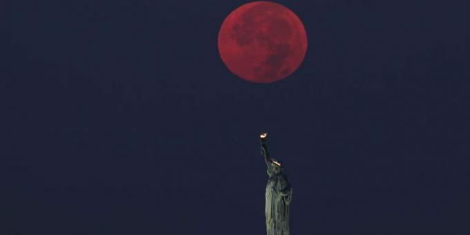 Der Vollmond geht hinter der Freiheitsstatue in New York City unter