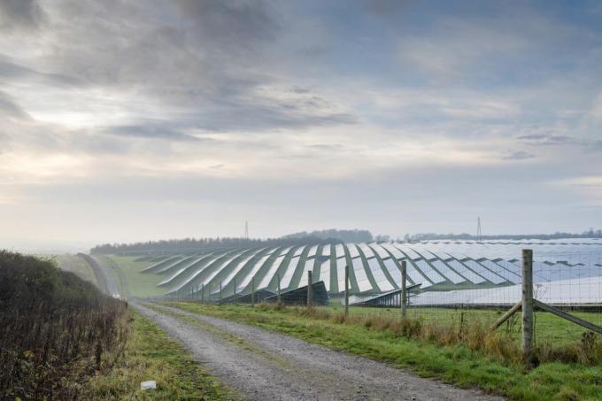 Solarenergiestandort im Herzen der englischen Landschaft, eingezäunt, daneben führt ein schmaler Feldweg ins Ackerland