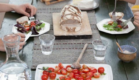 Schließen Sie oben von den Paaren, die bei Tisch mit Tomaten und Brot zu Mittag essen